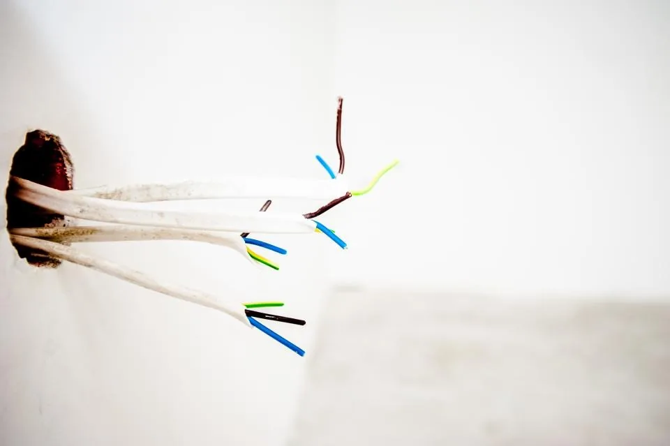 Cables eléctricos saliendo de una caja empotrada en la pared
