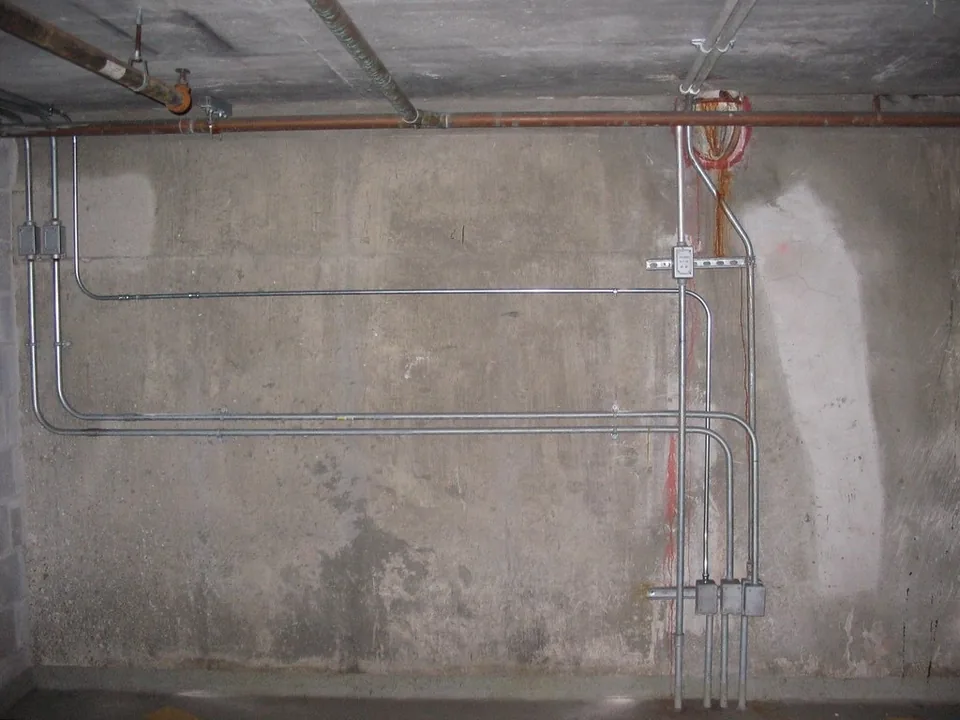 Tubos de instalación eléctrica fijados en la pared de un sótano